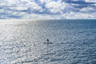 Gün batımında Menorca Denizi 'nde sörf yapan bir kadının silueti. Balear Adaları