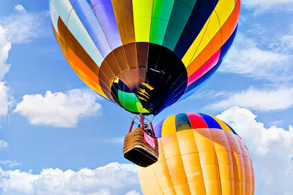 Mavi gökyüzünde beyaz bulutlarla uçan renkli sıcak hava balonu