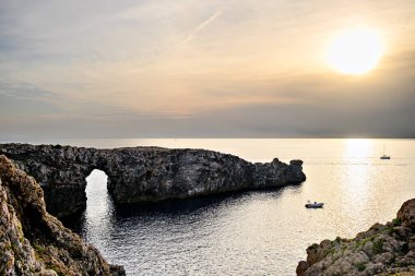 Ciutadella, Menorca, Balearic Adaları 'ndaki Pont den Gil Cala Corbetar' da muhteşem bir günbatımı. Kemer şeklinde tuhaf bir doğal oluşum.