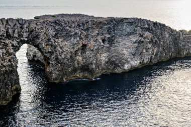 Ciutadella, Menorca, Balearic Adaları 'ndaki Pont den Gil Cala Corbetar' da muhteşem bir günbatımı. Kemer şeklinde tuhaf bir doğal oluşum.