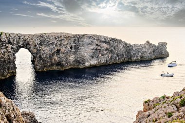 Ciutadella, Menorca, Balearic Adaları 'ndaki Pont den Gil Cala Corbetar' da muhteşem bir günbatımı. Kemer şeklinde tuhaf bir doğal oluşum.