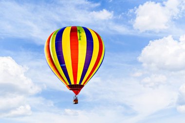 Mavi gökyüzünde beyaz bulutlarla uçan renkli sıcak hava balonu
