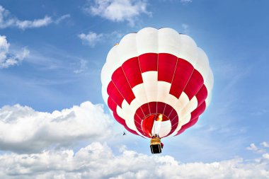 Mavi gökyüzünde beyaz bulutlarla uçan renkli sıcak hava balonu