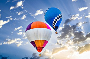Mavi gökyüzünde beyaz bulutlarla uçan renkli sıcak hava balonu