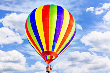 Mavi gökyüzünde beyaz bulutlarla uçan renkli sıcak hava balonu