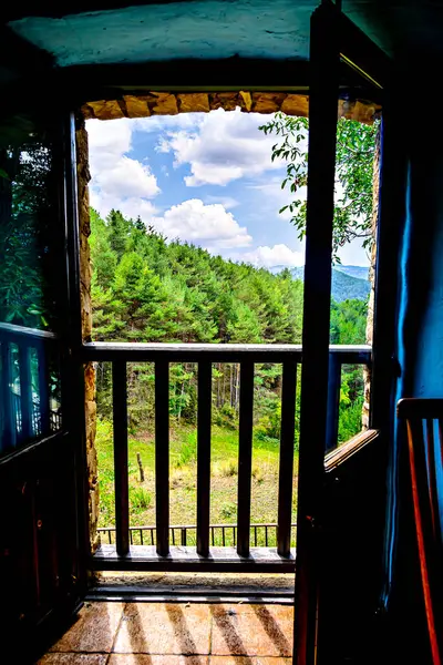 Kırsal bir evin penceresinden dağların, ağaçların ve doğanın güzel manzarasına bak.