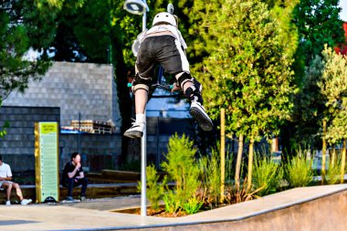 Igualada, Barcelona, Spain; June 25, 2023: Young man practicing Scootering (Freestyle Scootering) in the new SkatePark in the central park of Igualada clipart