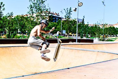 Igualada, Barcelona, İspanya; 25 Haziran 2023: Igualada Central Park 'taki yeni kaykay parkında Scootering (Serbest stil Scootering) uygulayan genç adam