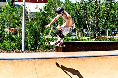Igualada, Barcelona, İspanya; 25 Haziran 2023: Igualada Central Park 'taki yeni kaykay parkında Scootering (Serbest stil Scootering) uygulayan genç adam