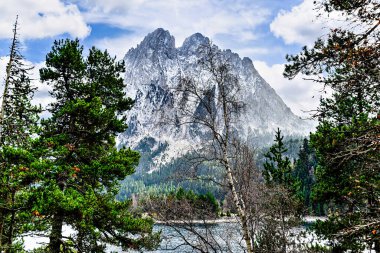 Image of Sant Maurici Lake with snow-capped mountains, in the Aiges Tortes National Park, in the Lleida Pyrenees, Catalonia, Spain clipart