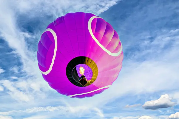 Mavi gökyüzünde beyaz bulutlarla uçan renkli sıcak hava balonu