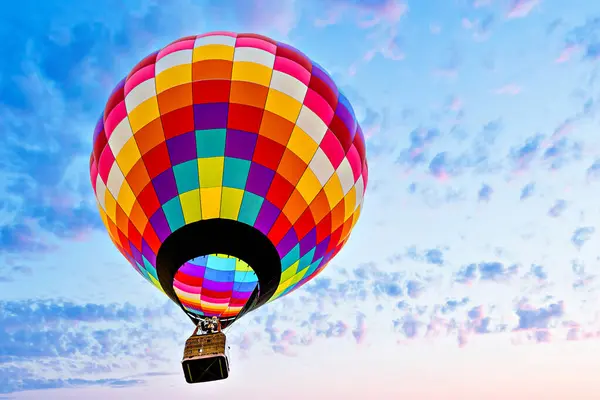 Mavi gökyüzünde beyaz bulutlarla uçan renkli sıcak hava balonu