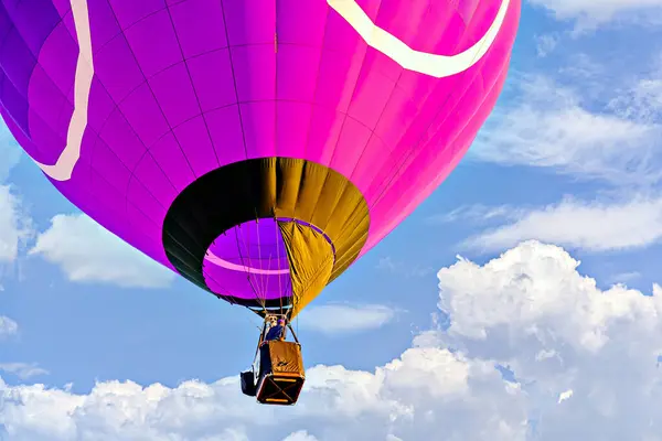 Mavi gökyüzünde beyaz bulutlarla uçan renkli sıcak hava balonu