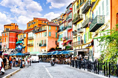 Villefranche-sur-Mer, Fransa; 20 Ağustos 2024: Renkli evleriyle turistlerle dolu Villefranche-sur-Mer 'in pitoresk köy ve plajının görüntüsü.