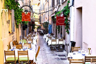 Saint-Tropez 'deki tipik bir cadde, yerel restoranlardan masa ve sandalyelerle dolu. Fransız Rivierası, Fransa