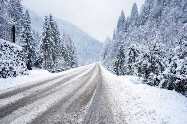 Kışın kar fırtınası sırasında dağlarda taze karla kaplı ıssız bir yol.