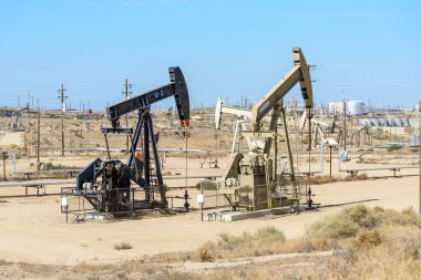 Sonbaharda mavi gökyüzünün altında petrol kuyuları. Bakersfield, CA, ABD.