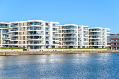 New apartment buildings along a river harbour on a clear summer day. Bremerhaven, Germany. clipart
