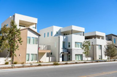 Newly built detached houses along a street in a housing development on a sunny autumn day. Santa Clarita, CA, USA.
