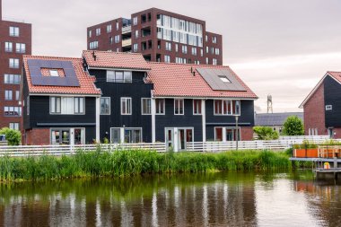 Energy efficient waterfront row houses with rooftop solar panels at sunset. Groningen, Netherlands.