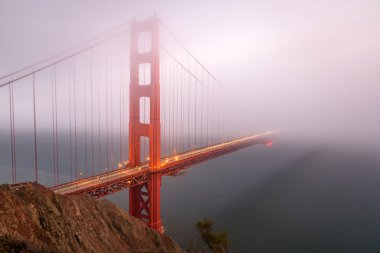 Sonbaharda alacakaranlıkta kalın sisle kaplanmış Altın Kapı Köprüsü. San Francisco, CA, ABD.