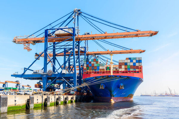 Large container ship being loaded in a harbour on a sunny summer day. Rotterdam, Netherlands