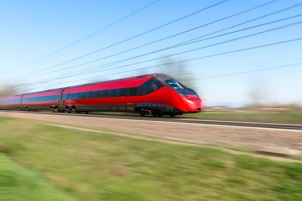 春の晴れた日に田舎を走る近代的な赤の高速旅客列車 モーションブラー効果 — ストック写真