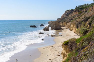 Güneşli bir sonbahar gününde Kaliforniya kıyıları boyunca gözlerden uzak güzel kumlu bir sahil. Malibu, CA, ABD.
