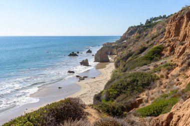 Güneşli bir sonbahar gününde, bir uçurumun eteğindeki tenha kumsalda. Malibu, CA, ABD.