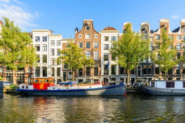 Yazın günbatımında Amsterdam şehir merkezinde bir kanal boyunca geleneksel Duch mimarisi