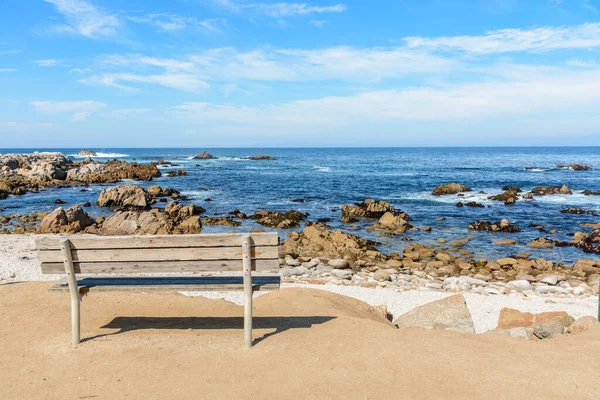 日当たりの良い秋の日に捨てられた岩のビーチの前に空の木製のベンチ 米国カリフォルニア州モントレー — ストック写真
