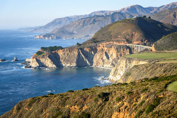 View of the rocky coast of California and Bixby bridge on sunny autumn afternoon. Big Sur, CA, USA.