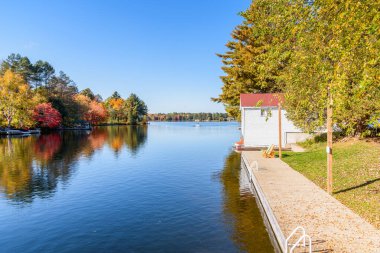 Açık bir sonbahar gününde, bir gölün kıyısındaki boş ahşap rıhtım. Baysville, ON, Canada.