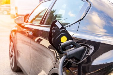 Güneşli bir yaz gününde Chester, İngiltere, İngiltere 'de şarj olan elektrikli bir arabaya bağlı bir kabloyu kapatın..