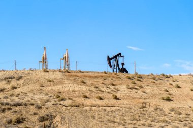 Açık bir sonbahar gününde çöl tepesinde petrol çıkarma için pompalar. Bakersfield, CA, ABD.