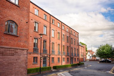 Parçalı bulutlu bir yaz gününde bir yerleşim bölgesindeki cadde boyunca yenilenmiş apartman blokları. Chester, İngiltere, İngiltere.