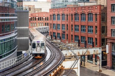 Chicago yağmurlu bir bahar gününde şehir merkezinde viraj raylarında yükselen banliyö treni. Illinois, ABD.