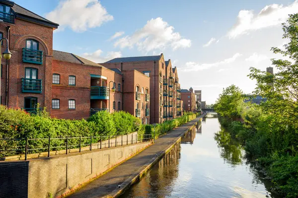 Yazın gün batımında bir kanal boyunca inşa edilen tuğla apartmanlar ve depoları yeniledi. Chester, İngiltere, İngiltere.