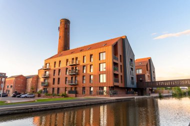 Gün batımında temiz bir gökyüzü altında tarihi tuğla bir kule tarafından gözden kaçırılan yeni apartmanlar. Chester, İngiltere, İngiltere.