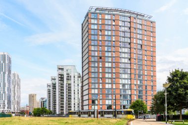 Parçalı bulutlu bir yaz gününde, banliyöde inşa edilen modern, yüksek katlı apartmanlar. Önden geçen bir tramvay görülebilir. Manchester, İngiltere, İngiltere.