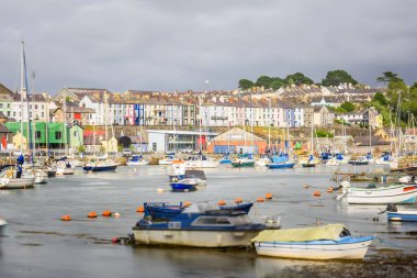 Limana gökyüzü fırtınası altında renkli teraslı evler yığılmış durumda. Caernarfon, Galler, İngiltere.