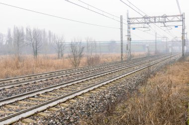 Issız bir kış sabahı kırsal kesimde bir otoyol köprüsünün altından geçen terk edilmiş bir tren yolu.