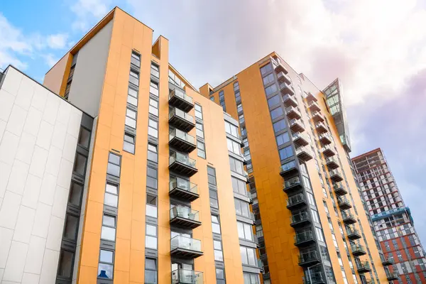 Yazın parçalı bulutlu gökyüzü altında modern yüksek apartman blokları. İnşaat halindeki bir bina uzaktan görülebilir. Manchester, İngiltere, İngiltere.