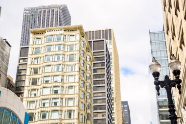 Parçalı bulutlu bir bahar gününde Chigaco Loop bölgesinde modern ofis gökdelenleriyle çevrili geleneksel bir apartmanın alçak açılı görüntüsü. Illinois, ABD.