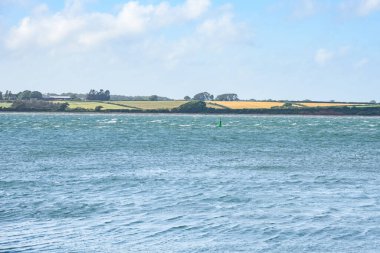 Açık bir yaz gününde rüzgarlı bir sahil boyunca tarım arazileri. Caernarfon, Galler, İngiltere.