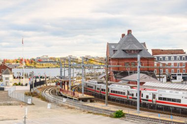 Parçalı bulutlu bir sonbahar gününde, rıhtımdaki eski bir tuğla istasyonunda banliyö treni. New London, CT, ABD.