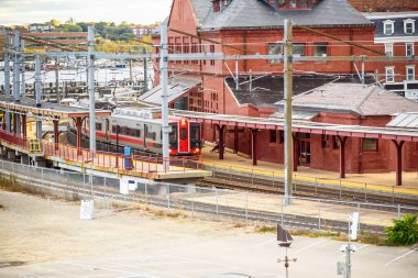 Elektrikli yolcu treni güneşli bir sonbahar gününde geleneksel bir tren istasyonuna giriyor. New London, CT, ABD.