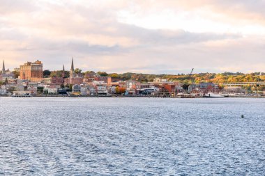 Sonbaharda günbatımında parti bulutlu gökyüzünün altındaki bir rıhtımda geleneksel tuğla binalar. New London, CT, ABD.