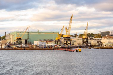 Sonbaharda günbatımında büyük sarı vinçleri olan Riverside üretim tesisi. Groton, CT, ABD.