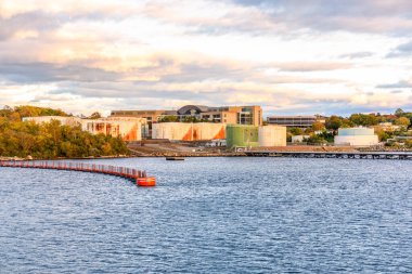 Sonbaharda gün batımında nehir kenarındaki bir petrol terminalinde paslı yakıt tankları. Groton, CT, ABD